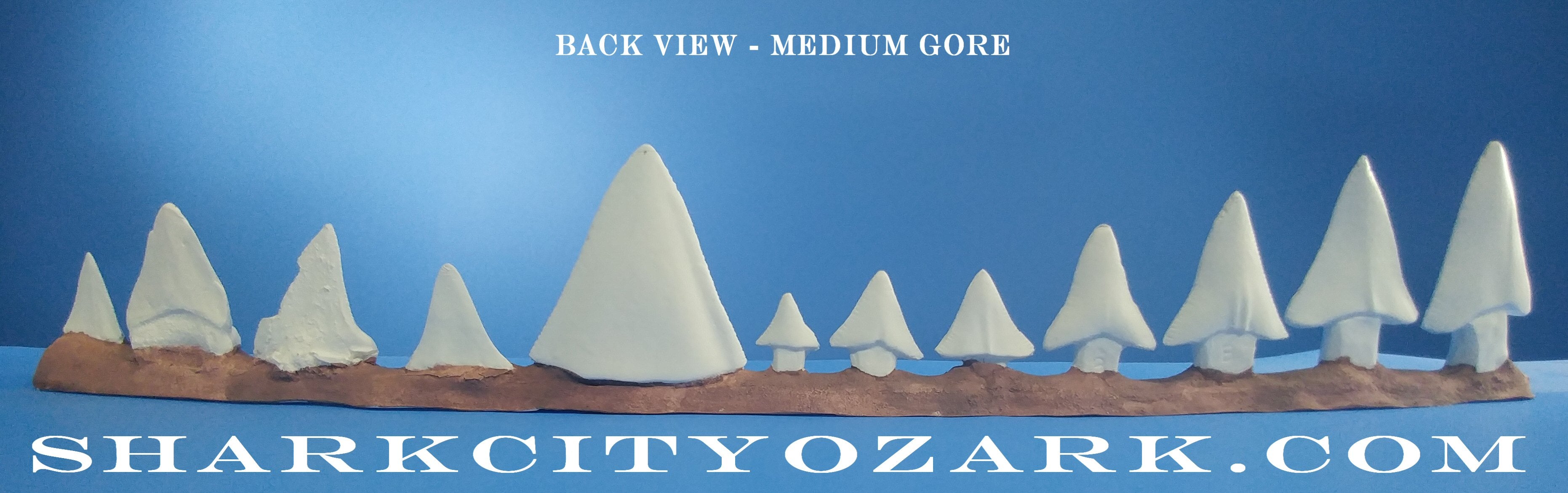 Decorative set of white shark models on a wooden base with a blue background and text. Jaws Megaladon shark teeth