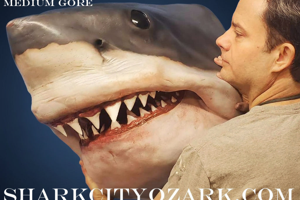 Man with a shark's head against a blue sky, promoting 'Shark City Ozark'. great white shark