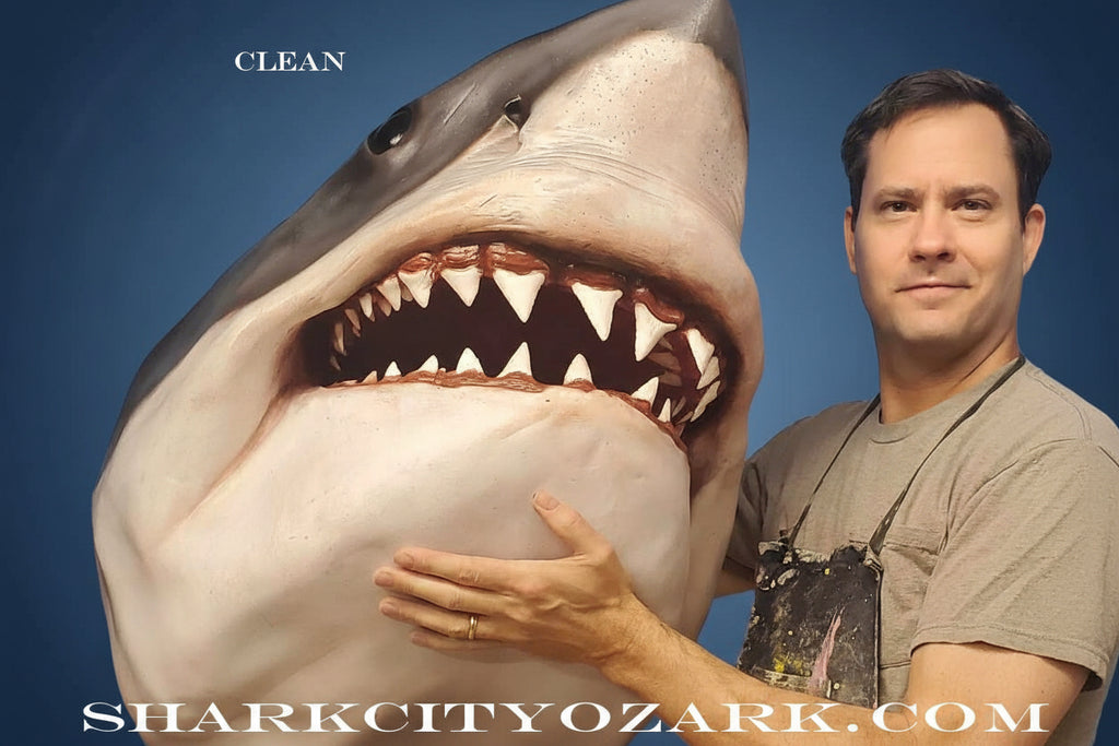 Man standing next to a large shark model with 'Shark City Ozark' website displayed. great white shark
